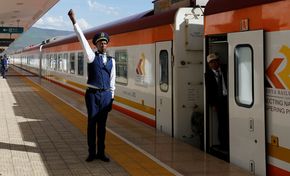 Ein Mitarbeiter der Kenya Railway gibt das Abfahrtssignal für einen Zug der Bahnlinie Mombasa-Nairobi- Naivasha. Die Strecke der Standard Gauge Railway (SGR) wurde durch einen chinesischen Konzern realisiert.