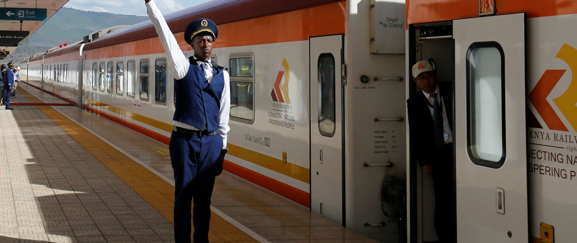 Ein Mitarbeiter der Kenya Railway gibt das Abfahrtssignal für einen Zug der Bahnlinie Mombasa-Nairobi- Naivasha. Die Strecke der Standard Gauge Railway (SGR) wurde durch einen chinesischen Konzern realisiert.