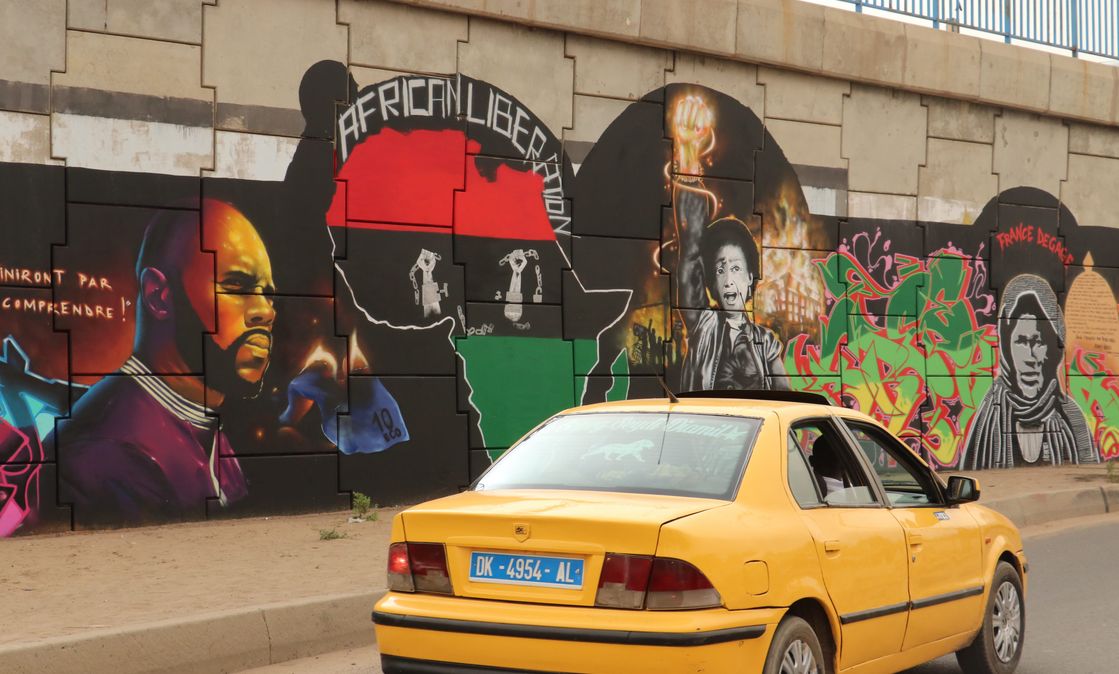 June 2020, Dakar, Senegal: A car drives past a mural by the graffiti artist collective "RBS Crew" picturing the anti-CFA activist Kémi Séba.