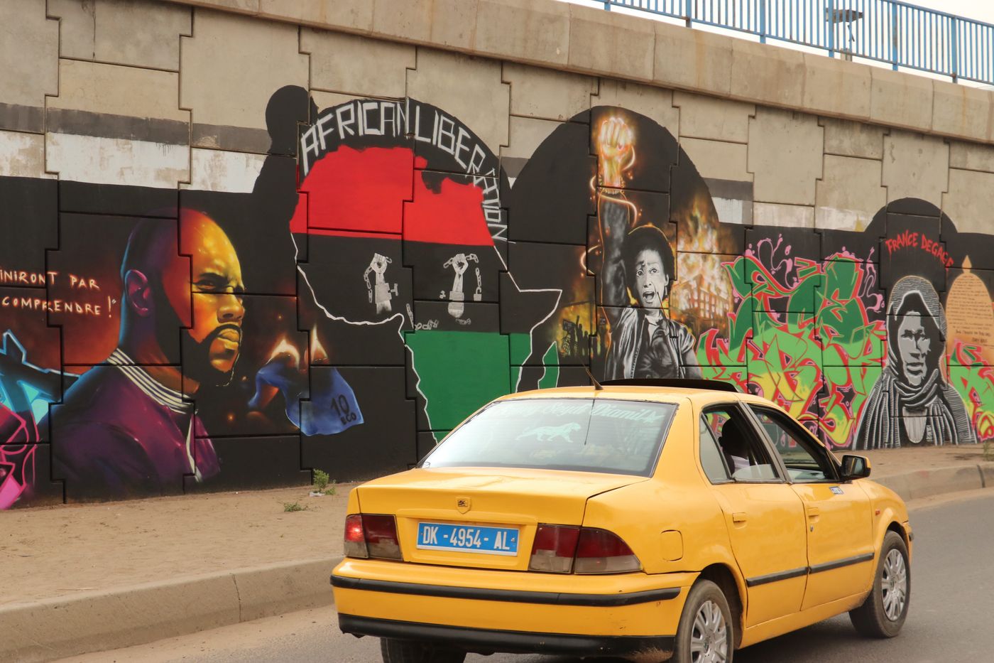 June 2020, Dakar, Senegal: A car drives past a mural by the graffiti artist collective "RBS Crew" picturing the anti-CFA activist Kémi Séba.